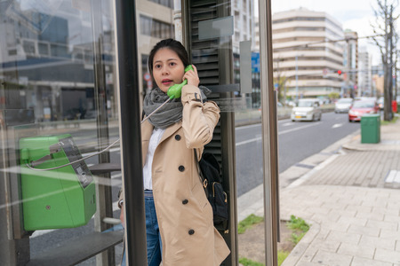 pretty female tourist using payphone to call and chat with her friend