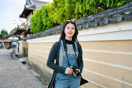 an elegant female photographer holding camera and walking in the streetの写真素材