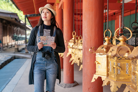 a confident female tourist visiting the temple with her guidebook