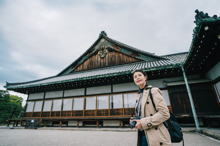 elegant tourist holding her camera, sightseeing the famous Japanese temple. Travel in Kyoto in Japan. female backpacker visiting Japan alone in spring.の写真素材