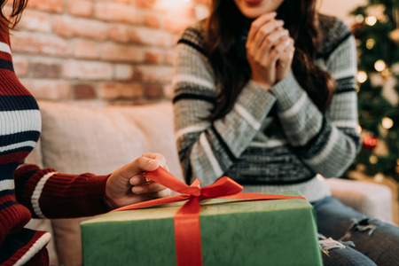 young ladies opening the present at home. girl pulling the ribbon to open the gift box. Merry...