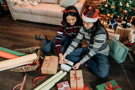 girls prepare presents for coming up new year and xmas. young ladies doing artwork at home. tie the ribbon on the box as christmas gift on boxing day.の写真素材