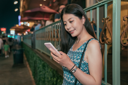 young asian girl relying outside the restaurant on the street in las vegas. elegant lady using using cellphone texting sms message. attractive woman nightlife in USA.の写真素材