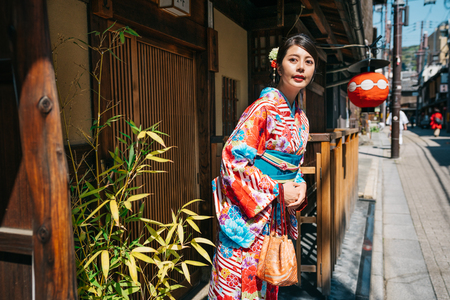 Japanese young girl wearing kimono and going out from home to join the big event in the town. teenager going to town center for festival with kimono clothing. Japanese young people holiday lifestyle.の写真素材