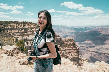 young female photographer photography of wild nature view in summer vacation. lady travel backpacker visit enjoying view of grand canyon national park america. beautiful girl face to camera smiling.の写真素材