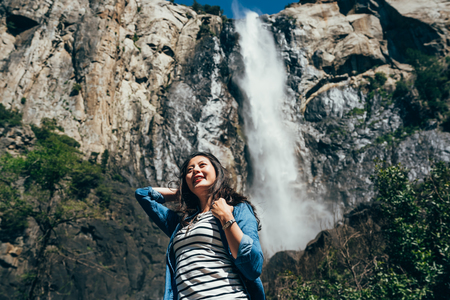 freedom woman love nature wild hiking in yosemite national park. beautiful female backpacker visit bridal veil falls relaxing face to sunlight enjoying. young lady traveler vacation trip in usa.の写真素材
