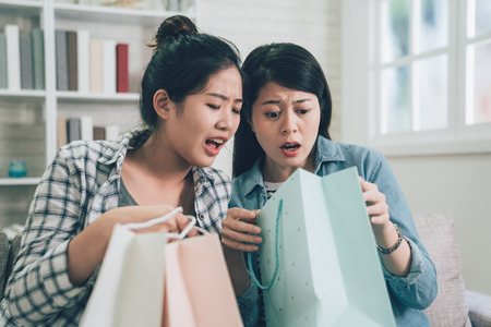 two asian unhappy shocked woman receiving wrong parcel with unsatisfied face.の写真素材