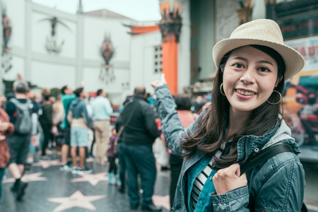 young smiling asian traveler woman in straw hat finger point showing background of famous chinese...
