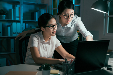 two asian business woman working discuss with laptop  in office at night.の写真素材