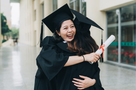 student girls hugging at school celebrating in graduation ceremony.の写真素材