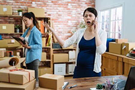 Angry pregnant businesswoman arguing on mobile phone.