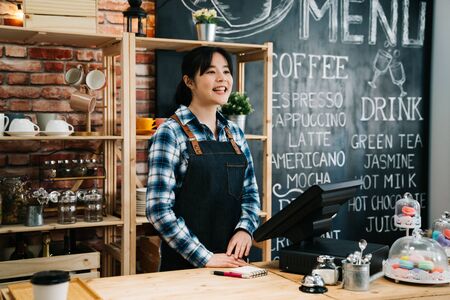 female small business owner with coffee shop menu on blackboard background.の写真素材