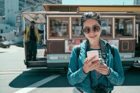 Beautiful asian woman traveler wearing sunglasses walking outdoors on city street and using mobile phone.の写真素材