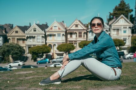 smiling young girl in sunglasses relax sitting on meadow on sunny day. famous attraction of painted...