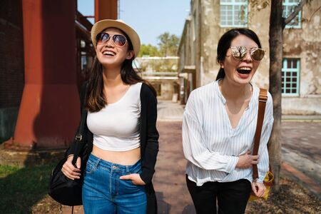young smiling asian japanese women in sunglasses walking and talking in sunset time outdoor. Happy...