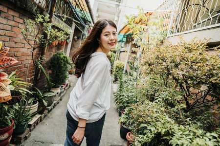 young beautiful asian japanese girl walking in little walkway surrounding by red brick old house in...
