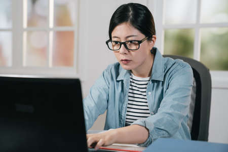 Smiling girl student using laptop computer studying at home. female teenager in glasses typing on...