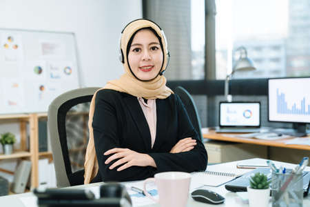 Beautiful phone operator Arab woman working in modern startup office. young muslim lady customer...