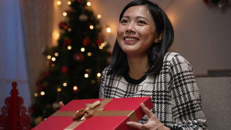 asian Japanese woman feeling disappointed with her Christmas gift and forcing smile while pretending...