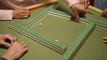 cropped view with closeup of a player's hand rolling dice in the center of table and counting stacks to decide which way to break the wall. mahjong game rule conceptの写真素材