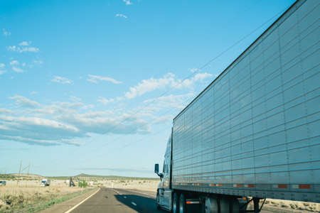 side view of driving almost parallel to freight truck on road. summer road trip overtaken by a big trailer.の写真素材