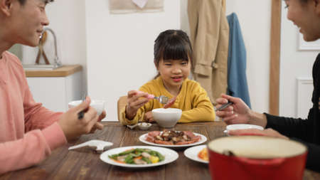 selective focus of picky Asian little girl eat the meat whit the fork at dining table homeの写真素材