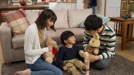 slow motion of asian dad, mom and baby son playing with toy animals on living room floor at home....