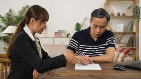 asian male pensioner putting signature on his long-term care insurance contract after consulting the...