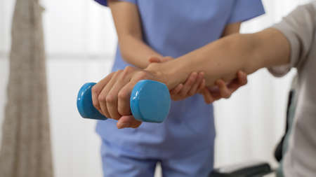 closeup shot hand of disabled person going through rehab training using a dumbbell. cropped female...