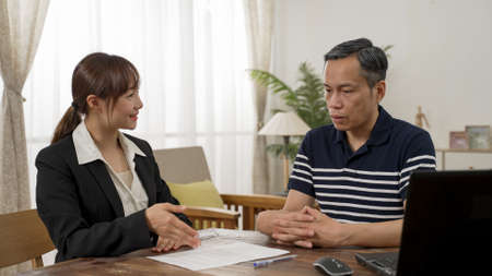 happy asian female insurance agent showing gratitude to the retired male client as he agrees to sign the contractの写真素材