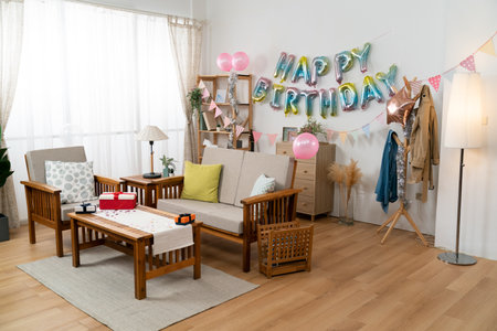 wide angle shot of a modern bright home interior with cute birthday party decoration  with birthday garland, pink balloons and giftsの写真素材