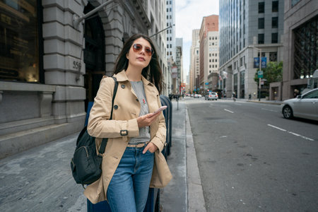 asian Japanese business lady holding phone and looking into distance with hand in pocket while waiting for client on the street in city urban of san Francisco in California usaの写真素材