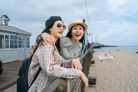 travel lifestyle and people on vacation in usa. two happy asian taiwanese girl visitors looking at beautiful sand beach at the pier of santa Barbara harbor in californiaの写真素材