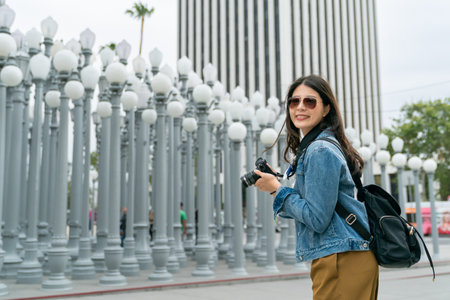 asian female tourist wearing sunglasses is looking at camera lens with big smile.の写真素材