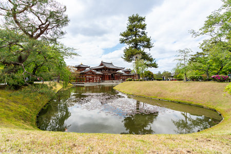Kyoto, Japan - April 18, 2018: the phoenix hall of Byodoin Temple at distance and lake water surrounded by green meadowland on a sunny day in uji at springtimeのeditorial素材