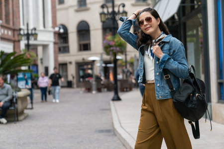 cheerful woman pushing back black hair with hand is visiting a foreign country.の写真素材