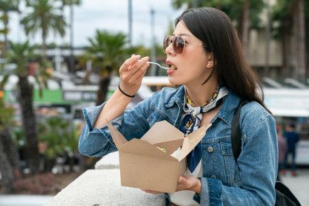 Asian Taiwanese backpacker girl enjoying street food as lunch on the street to experience local life in Los Angeles USAの写真素材