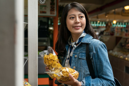 Asian customer female is choosing sweet dry bananas in organic shops. woman holding food and looking around with a smile.の写真素材