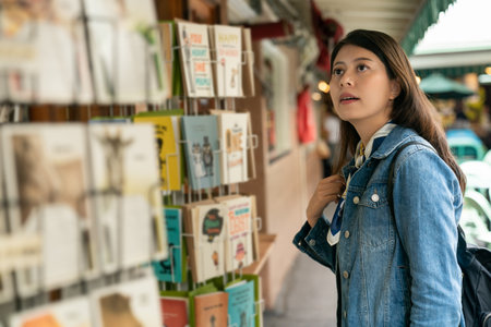 Tourist Asian Japanese pretty girl enjoying sightseeing exploring the city and buying postcards in the street shop.の写真素材
