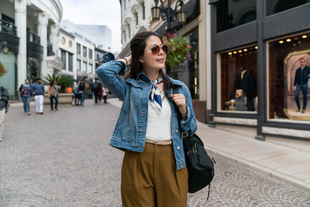 beautiful woman walking on pavement in leisure, admiring the streetscape while window shopping.の写真素材