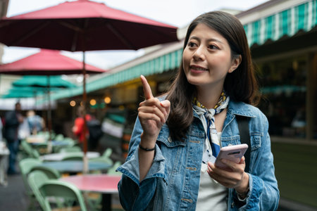 Smiling beautiful woman backpacker using phone searching direction on street.の写真素材