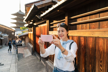 happy asian korean girl traveler having video chat with friend on cellphone at Ninenzaka and Sannenzaka in Kyoto japan while heading to Tower of Yasakaの写真素材