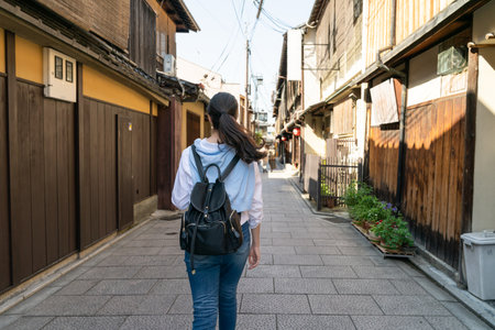 view from back asian Japanese woman visitor walking down alley lined with traditional wooden geisha houses on Gion Hanamikoji Street in Kyoto japanの写真素材