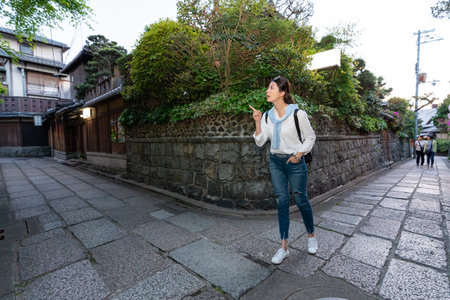 full length of asian korean female tourist finger pointing at space on the corner of stone paved streets while looking for directions at Ninenzaka and Sannenzaka in Kyoto japanの写真素材