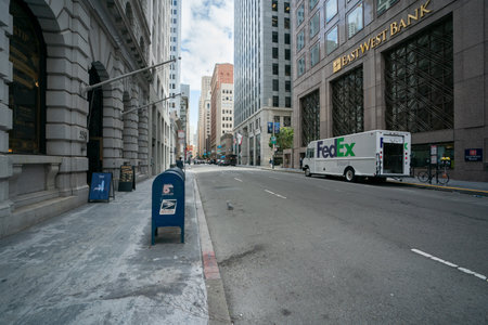 California, USA - May 16, 2018: FedEx delivery lorry truck stopping by east west bank building and blue post boxes on empty street among tall skyscrapers in downtown san Franciscoのeditorial素材