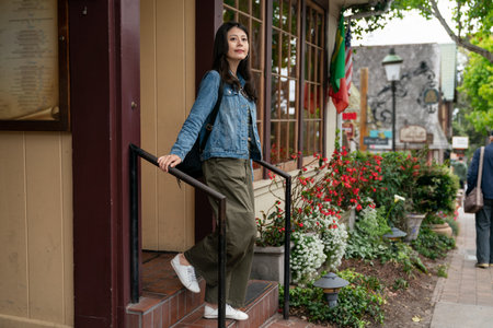 full length of cheerful asian Korean lady using stairs at entrance after having a satisfying meal at a local eatery in Carmel by the sea in California usaの写真素材