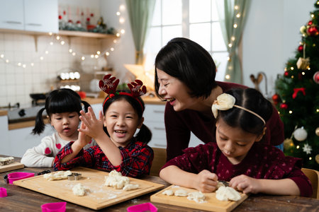 happy asian family smiling and feeling joy while preparing the dough for baking Christmas cookies together in the kitchen at homeの写真素材