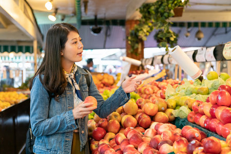 Asian woman buying fruit in a grocery store asks the clerk to help choose sweet and juicy fruit to make sweetの写真素材