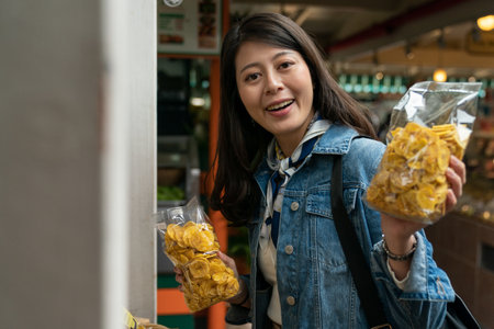 Asian Japanese backpacker girl goes to the local grocery store to buy food made from local fruit as a souvenir for a friend. looking at camera with smile.の写真素材