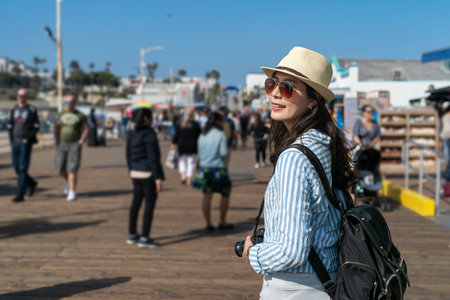 pretty stylish asian Chinese female backpacker having fun looking around at santa monica pier. travel lifestyle and spring holiday in united statesの写真素材